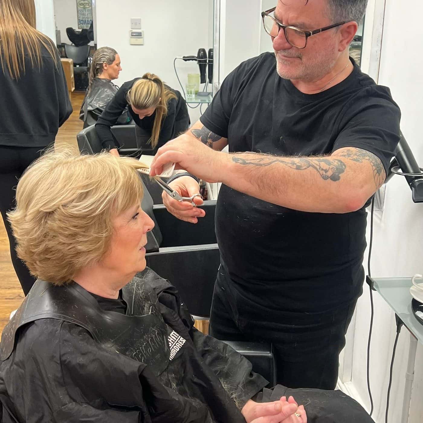 A stylist cutting a client's hair mid-consultation at The Establishment Hairdressing, Farnham