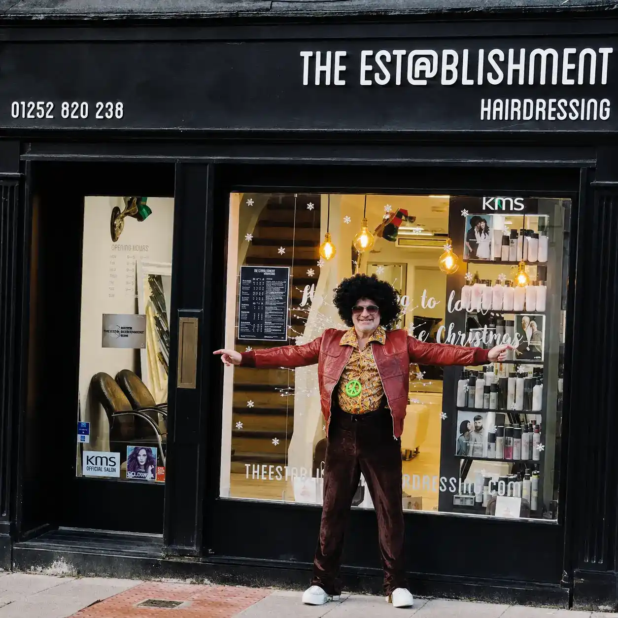 Ross outside The Establishment Hairdressing on Downing Street, Farnham · the founder, in a 70s afro and leather jacket, arms open wide