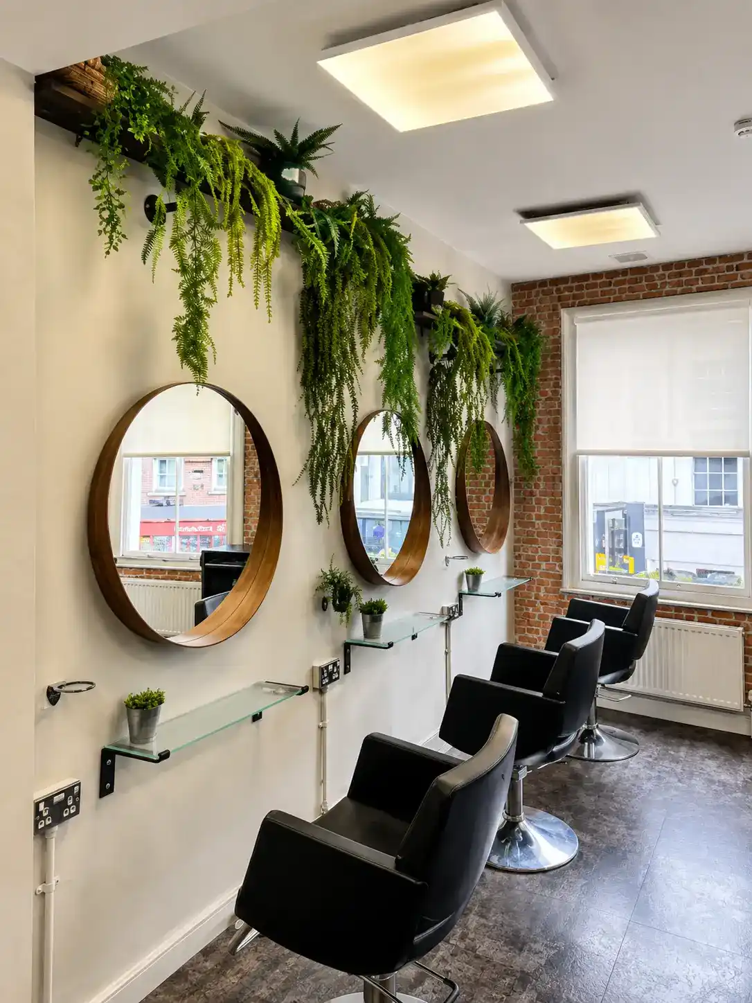 Styling stations and round mirrors at The Establishment Hairdressing, Farnham · trailing ferns and warm natural light