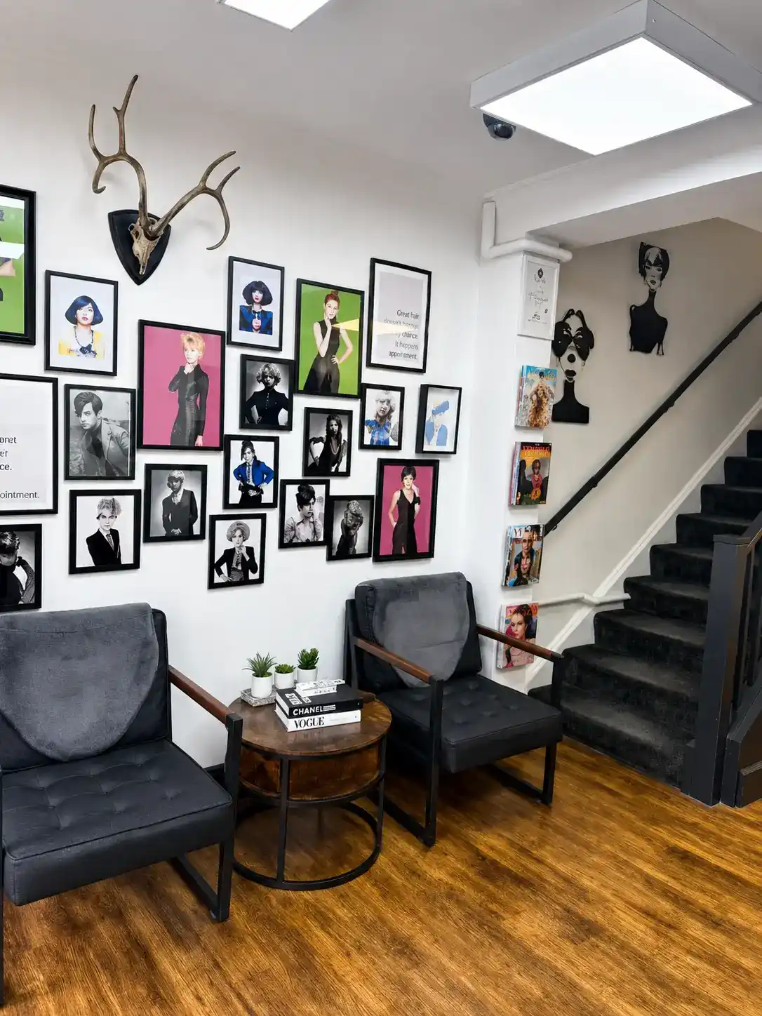 The waiting area at The Establishment Hairdressing · Vogue and Chanel coffee table books, velvet armchairs, editorial gallery wall and antler mount