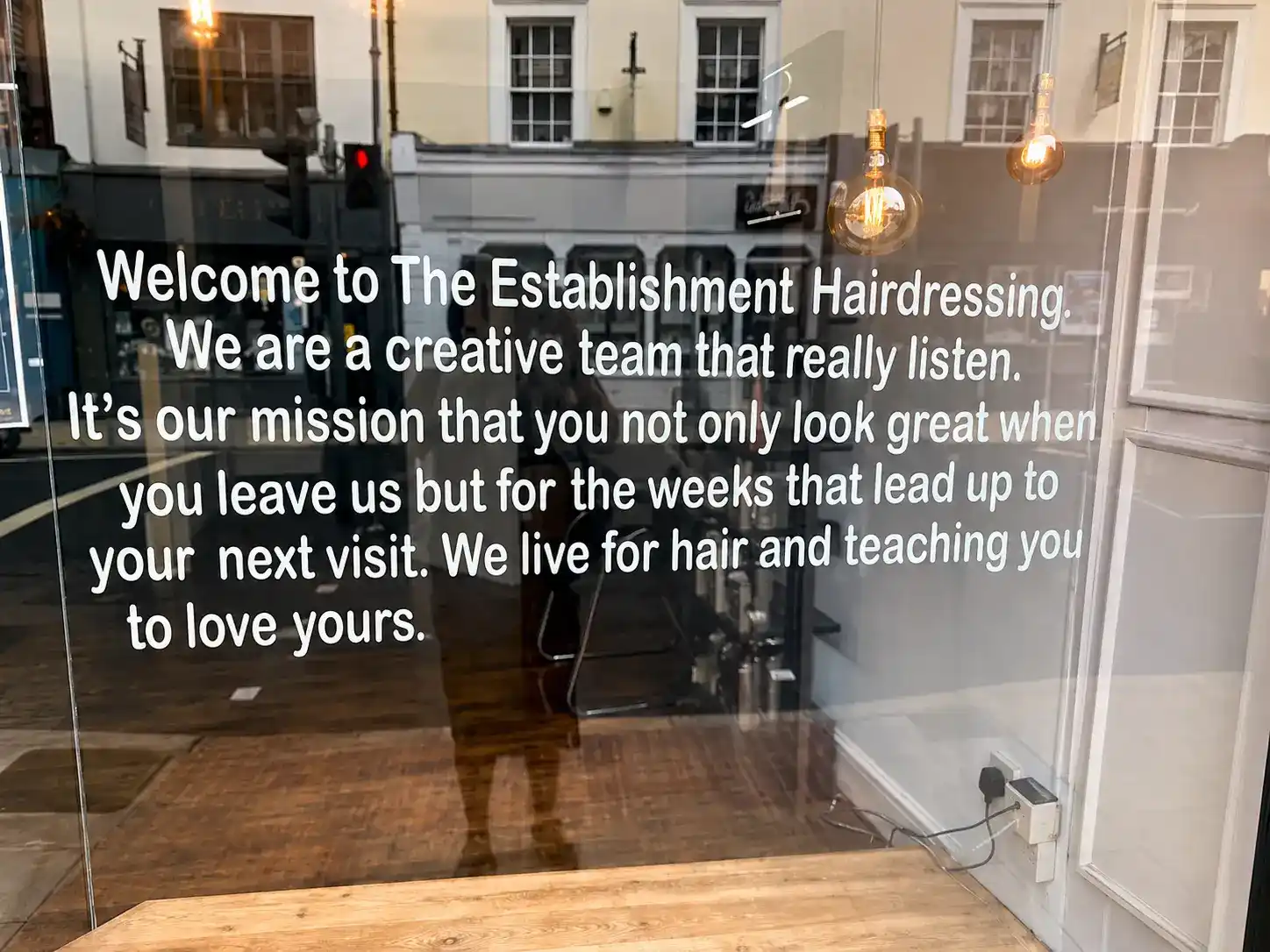 The Establishment Hairdressing shopfront window with mission statement, Downing Street, Farnham